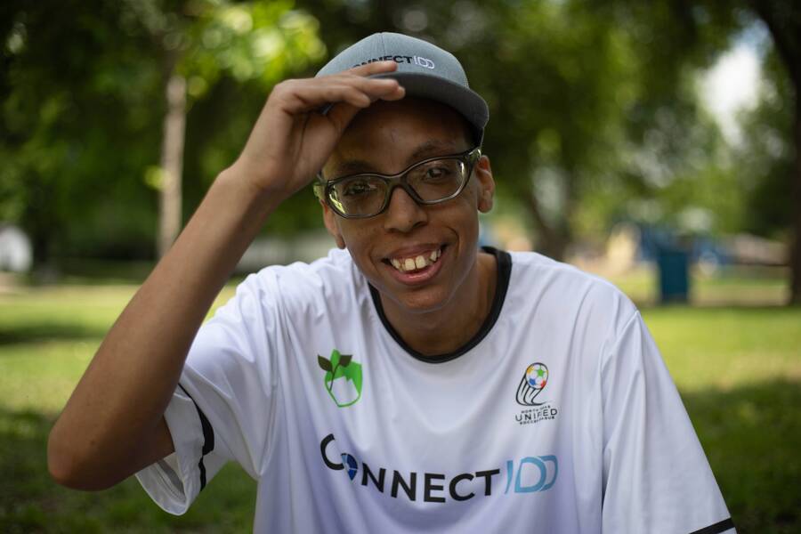 A young man in a ConnectIDD jersey tips his cap and smiles.