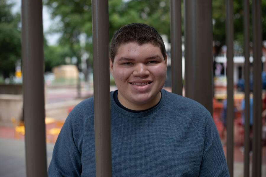 A smiling young man in a blue sweater.
